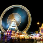 funfair carousel at night with the big merry-go-round wheel